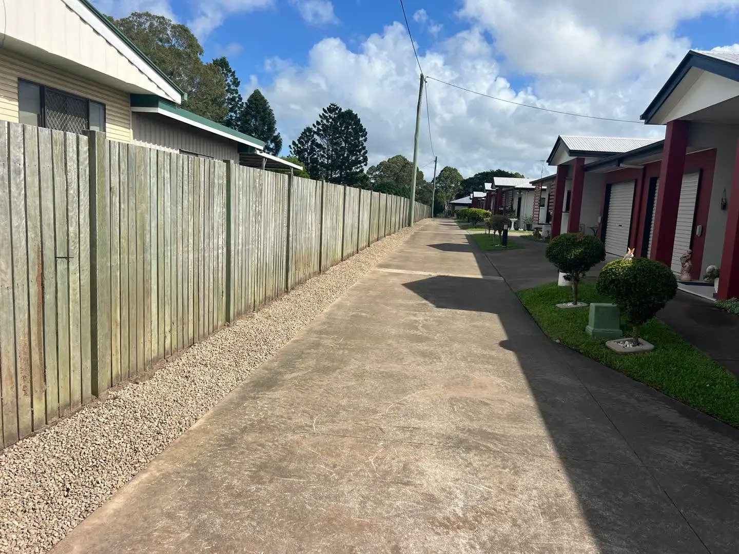 Cleared fence line after weeds were removed beside a residential driveway