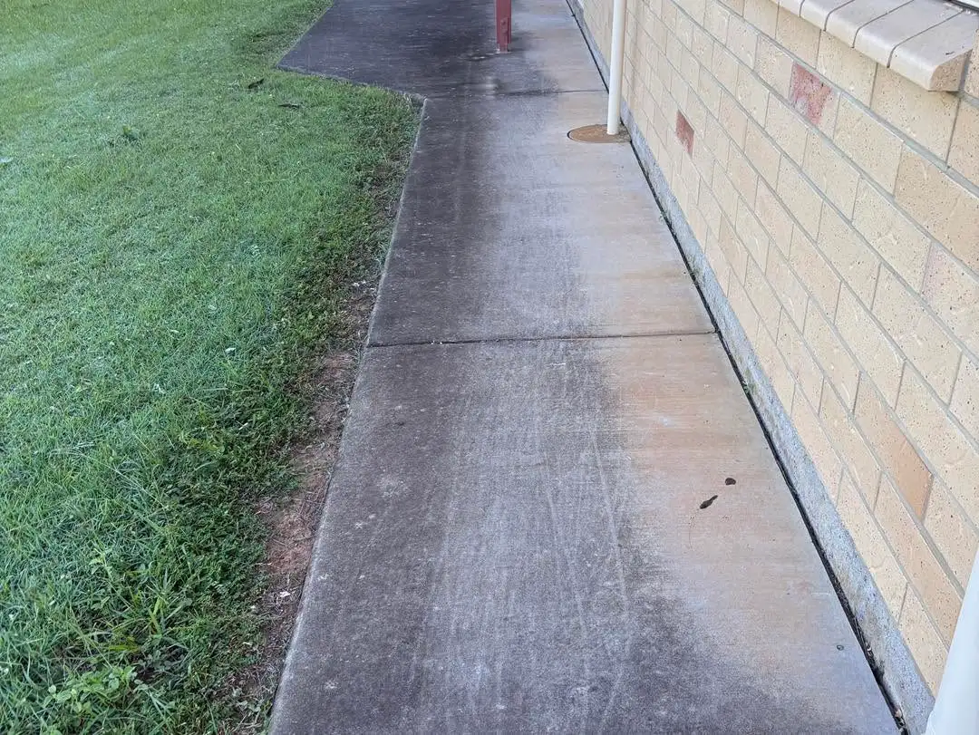 Dark stained concrete side path before pressure washing